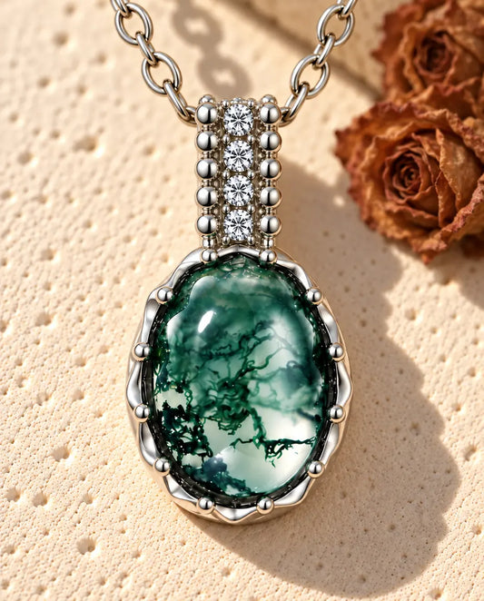Collier Agate Mousse Ovale en Argent 925 - posé sur une surface claire texturée près d’un bloc de travertin