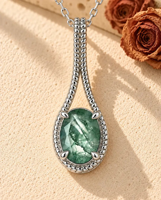 Collier Agate Mousse Ovale en Argent 925 - posé sur une surface claire texturée près d’un bloc de travertin