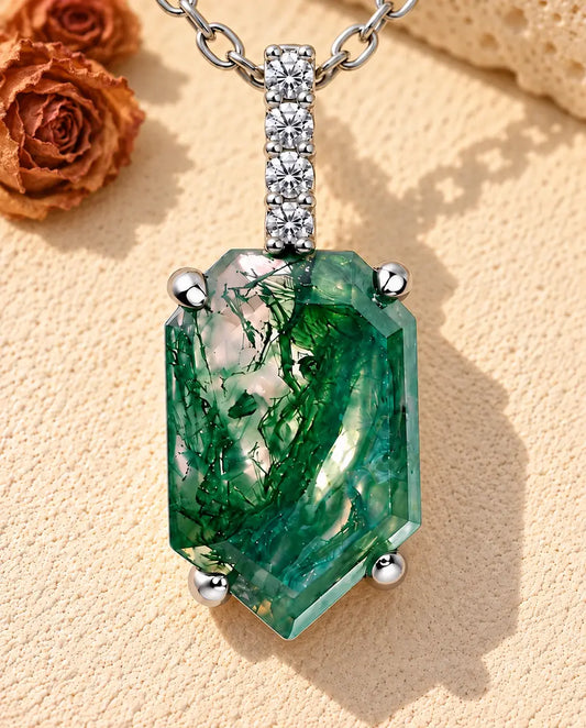 Collier Agate Mousse Pendentif Écusson en Argent 925 - posé sur une surface claire texturée près d’un bloc de travertin