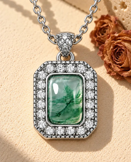 Collier Agate Mousse Halo en Argent 925 - posé sur une surface claire texturée près d’un bloc de travertin