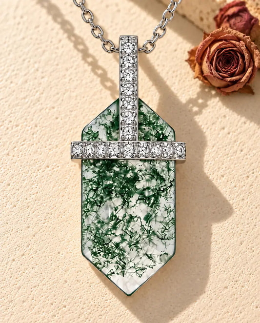 Collier Agate Mousse Hexagonale en Argent 925 - posé sur une surface claire texturée près d’un bloc de travertin