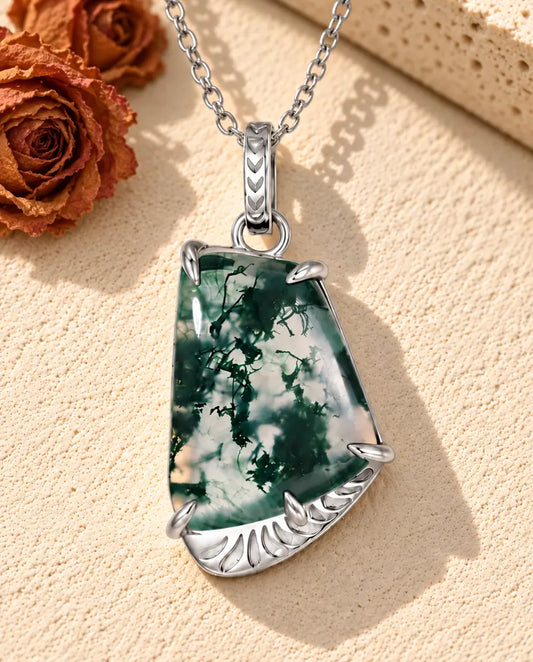 Collier Agate Mousse Forme Libre en Argent 925 - posé sur une surface claire texturée près d’un bloc de travertin