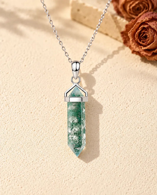 Collier Agate Mousse Pointe Hexagonale en Argent 925 - posé sur une surface claire texturée près d’un bloc de travertin