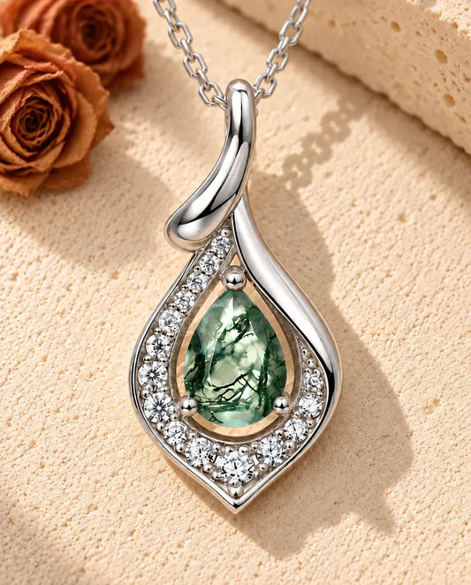 Collier Agate Mousse Poire en Argent 925 - posé sur une surface claire texturée près d’un bloc de travertin
