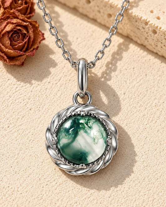 Collier Pendentif Agate Mousse Ronde en Argent 925 - posé sur une surface claire texturée près d’un bloc de travertin