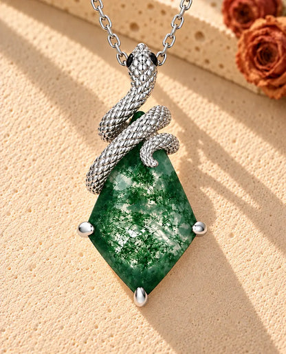 Collier Agate Mousse Serpent en Argent 925 - posé sur une surface claire texturée près d’un bloc de travertin