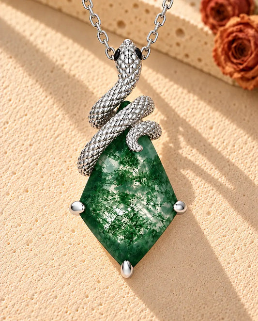 Collier Agate Mousse Serpent en Argent 925 - posé sur une surface claire texturée près d’un bloc de travertin