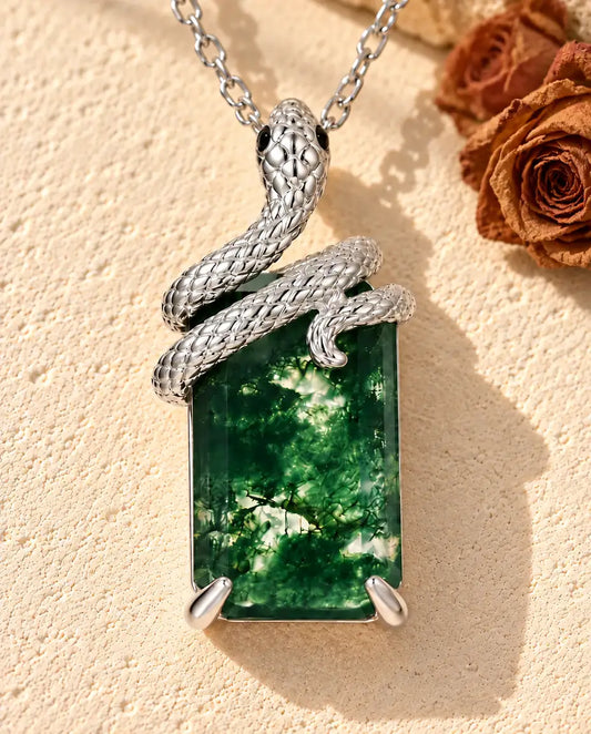 Collier Agate Mousse Serpent en Argent 925 - posé sur une surface claire texturée près d’un bloc de travertin