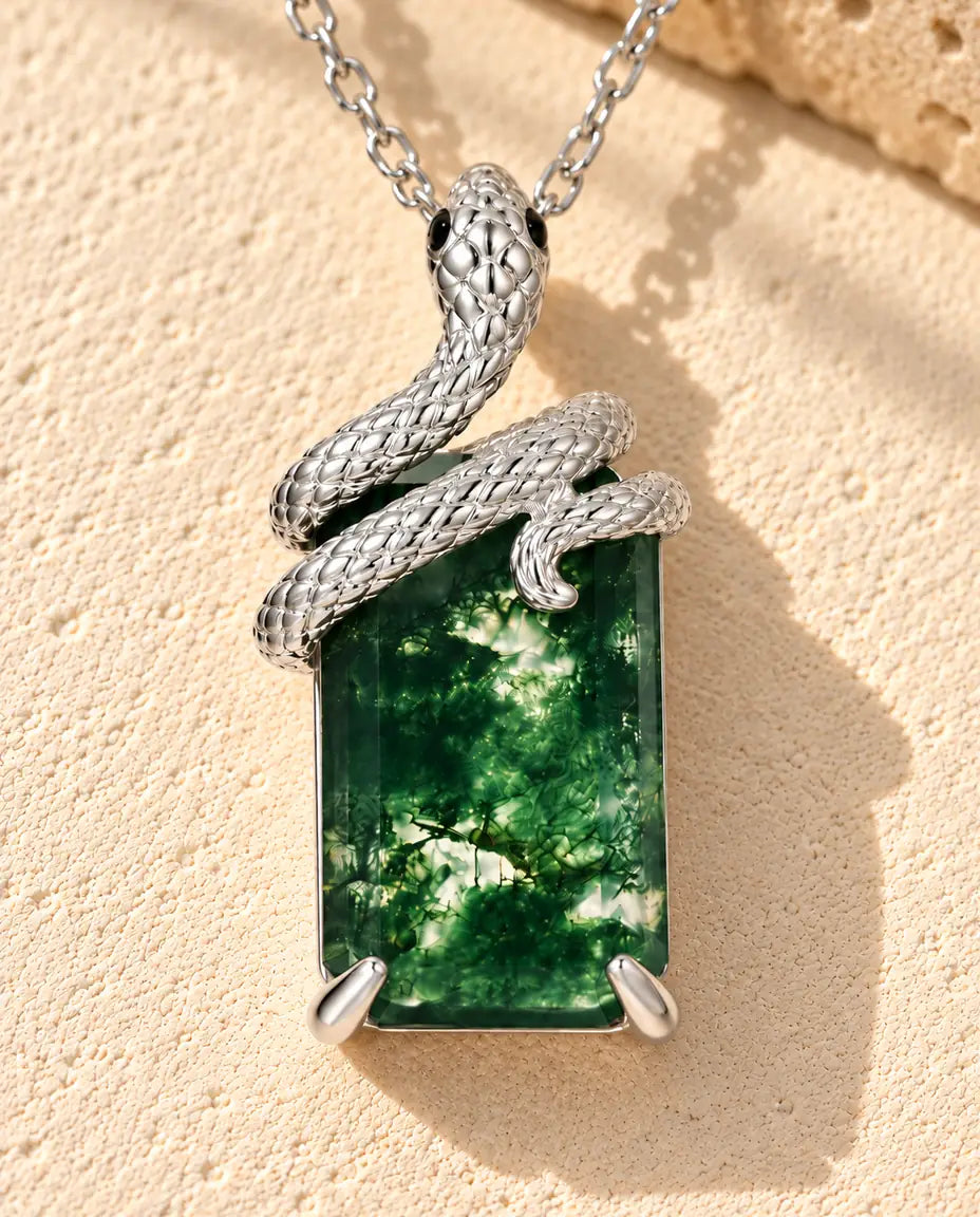 Collier Agate Mousse Serpent en Argent 925 - posé sur une surface claire texturée près d’un bloc de travertin