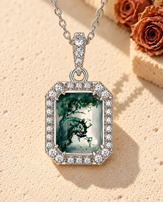 Collier Agate Mousse Taille Émeraude en Argent 925 - posé sur une surface claire texturée près d’un bloc de travertin