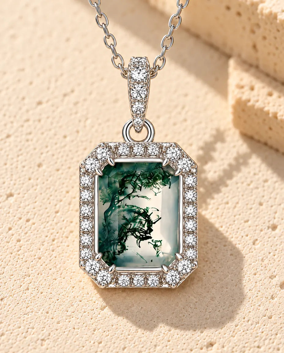 Collier Agate Mousse Taille Émeraude en Argent 925 - posé sur une surface claire texturée près d’un bloc de travertin