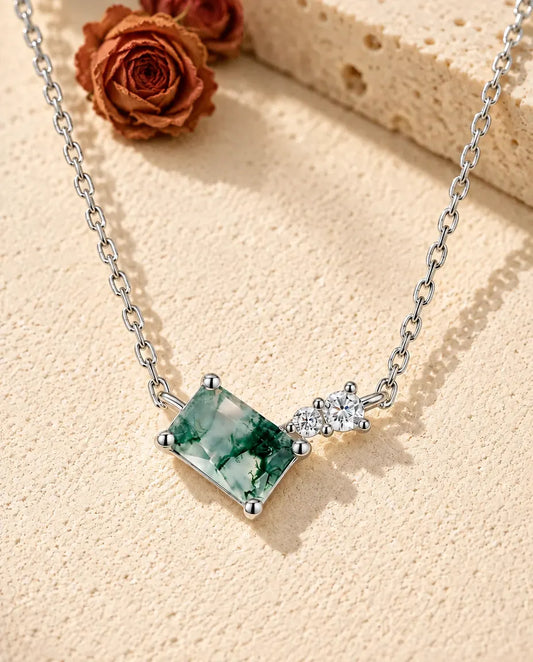 Collier Agate Mousse en Argent 925 - posé sur une surface claire texturée près d’un bloc de travertin