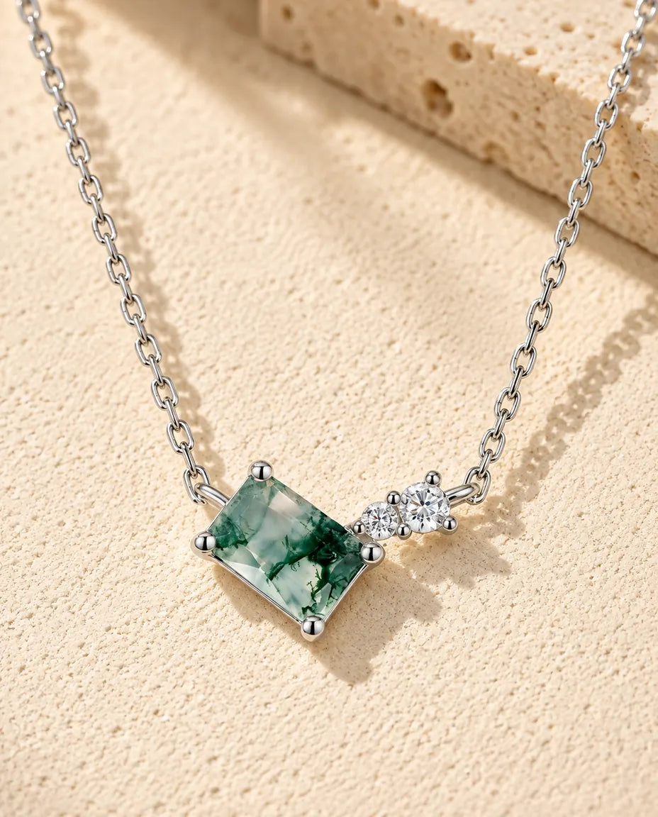 Collier Agate Mousse en Argent 925 - posé sur une surface claire texturée près d’un bloc de travertin