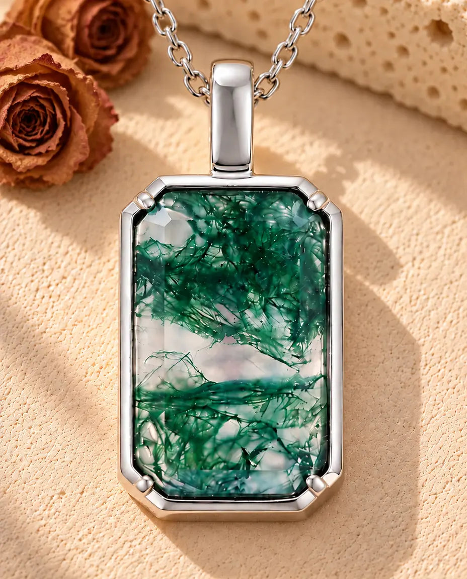 Collier Agate Mousse Pendentif Rectangle en Argent 925 - posé sur une surface claire texturée près d’un bloc de travertin