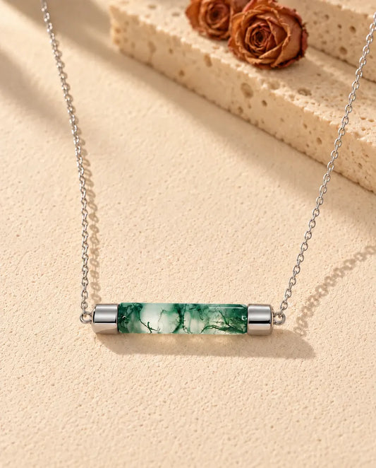 Collier Barre Agate Mousse en Argent 925 - posé sur une surface claire texturée près d’un bloc de travertin