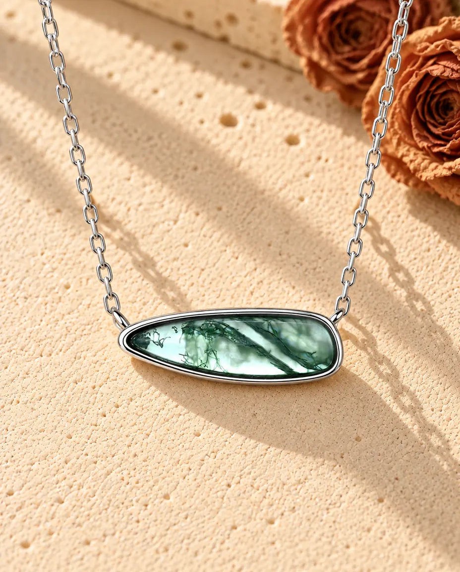 Collier Barrette Agate Mousse en Argent 925 - posé sur une surface claire texturée près d’un bloc de travertin