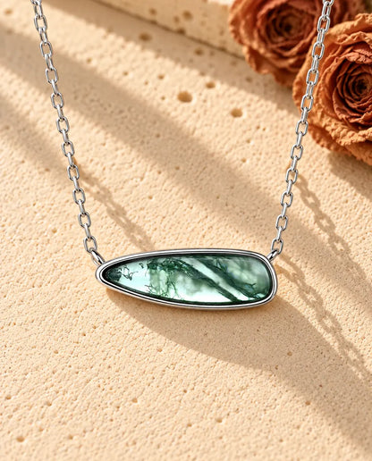 Collier Barrette Agate Mousse en Argent 925 - posé sur une surface claire texturée près d’un bloc de travertin