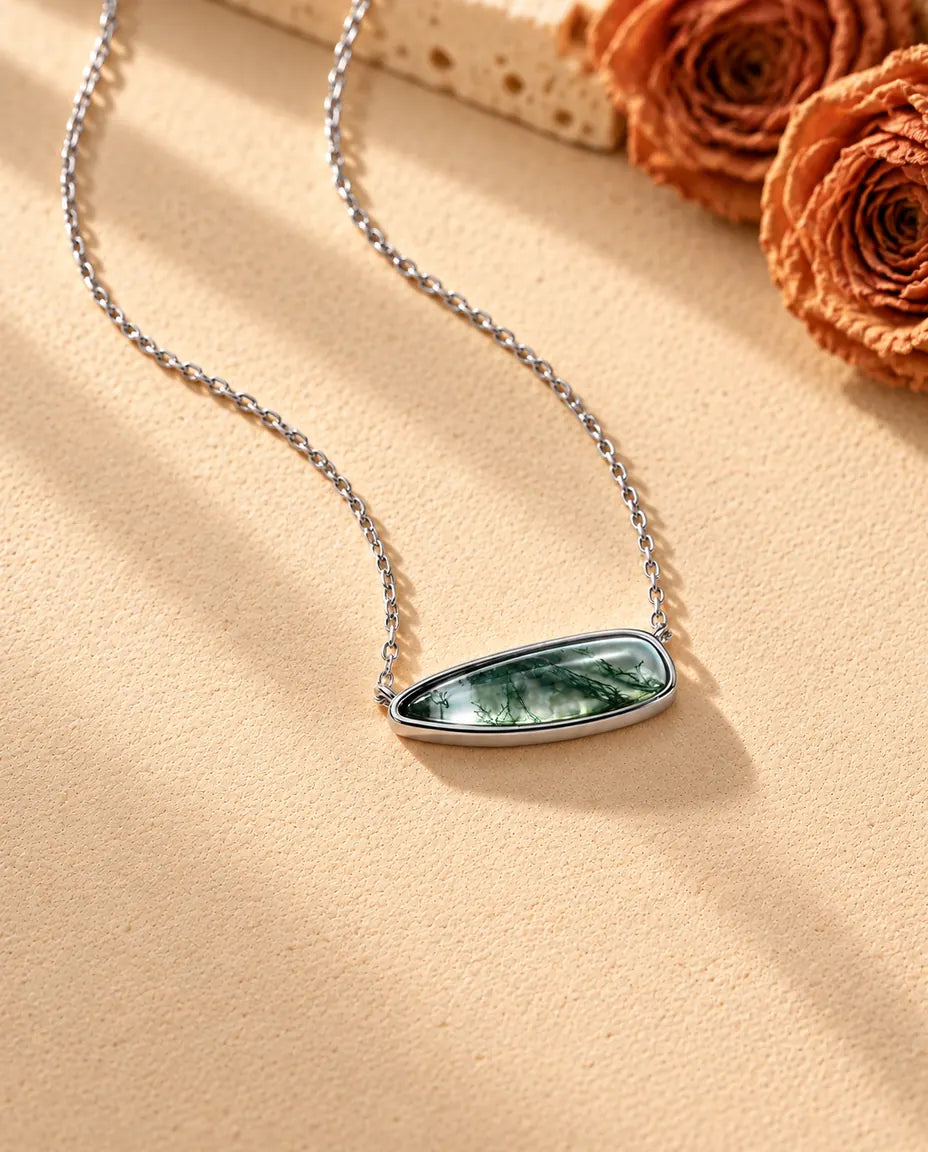 Collier Barrette Agate Mousse en Argent 925 - vu de biais sur une surface claire texturée
