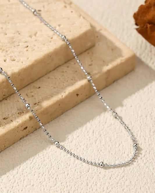 Collier Chaîne à Perles en Argent 925 - posé sur une surface claire près d’une dalle de travertin