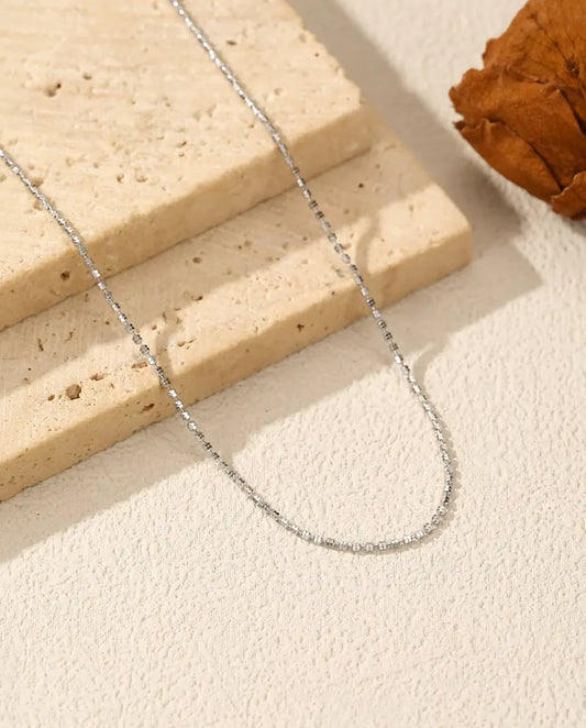 Collier Chaîne Diamantée en Argent 925 - posé sur une surface claire près d’une dalle de travertin
