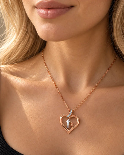 Femme portant le pendentif cœur père-fille couleur or rose avec un haut noir