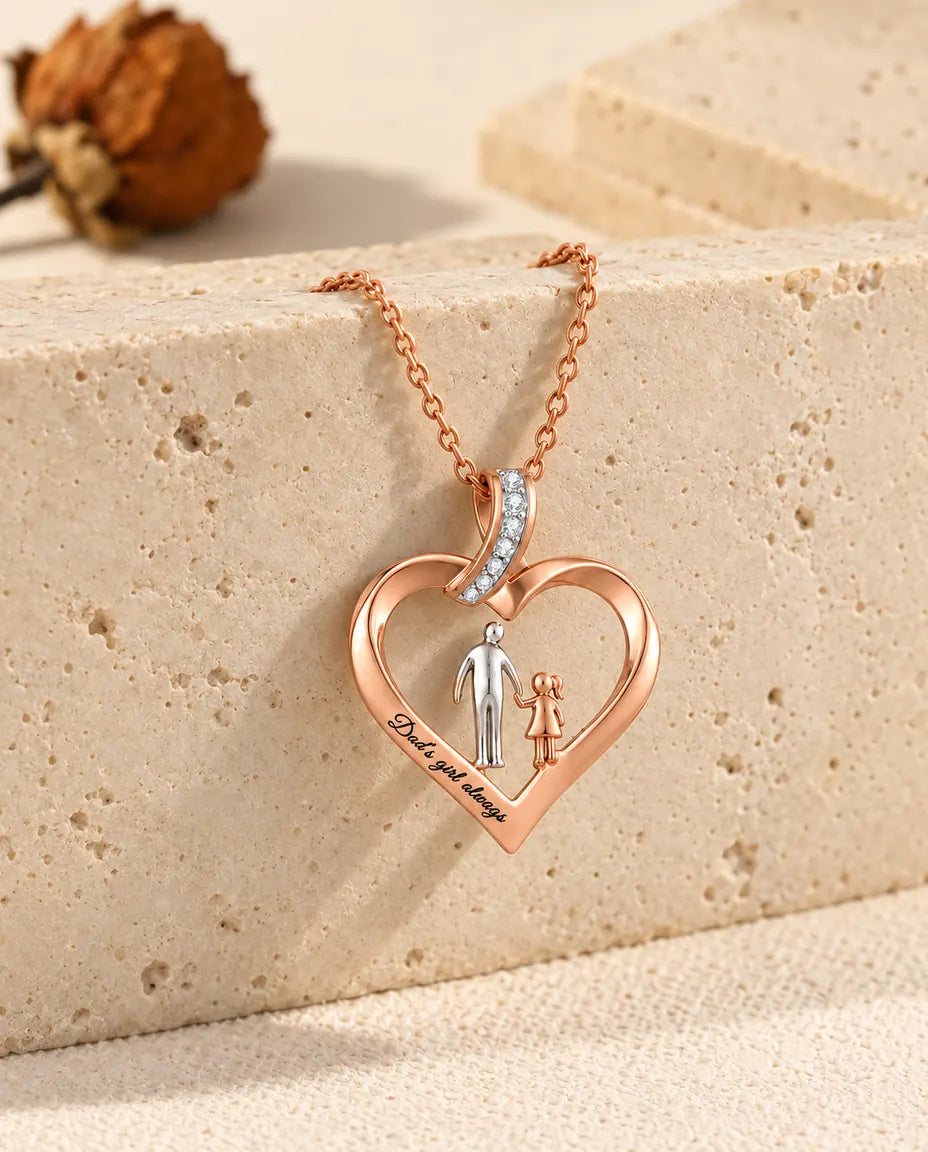 Collier cœur père-fille couleur or rose drapé sur le bord d'un bloc de travertin