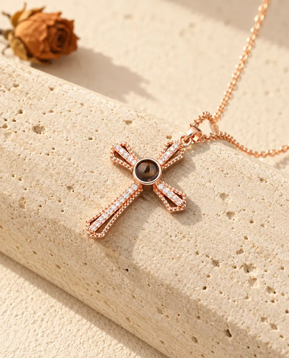 Croix couleur or rose sertie de zircons avec pierre de projection contre du travertin