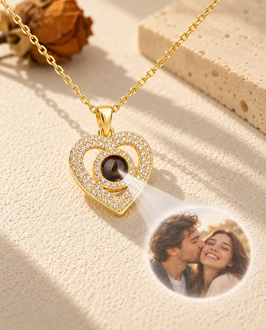 La lumière traverse la pierre du pendentif double cœur doré et projette la photo d'un couple