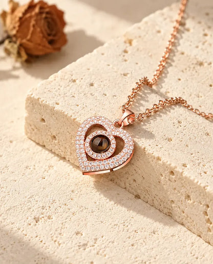 Pendentif double cœur couleur or rose pavé de zircons contre un bloc de travertin