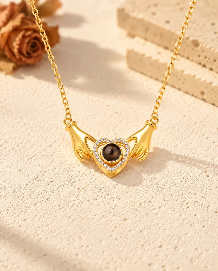 Vue de face du pendentif doré mains et cœur, la chaîne fixée à chaque poignet