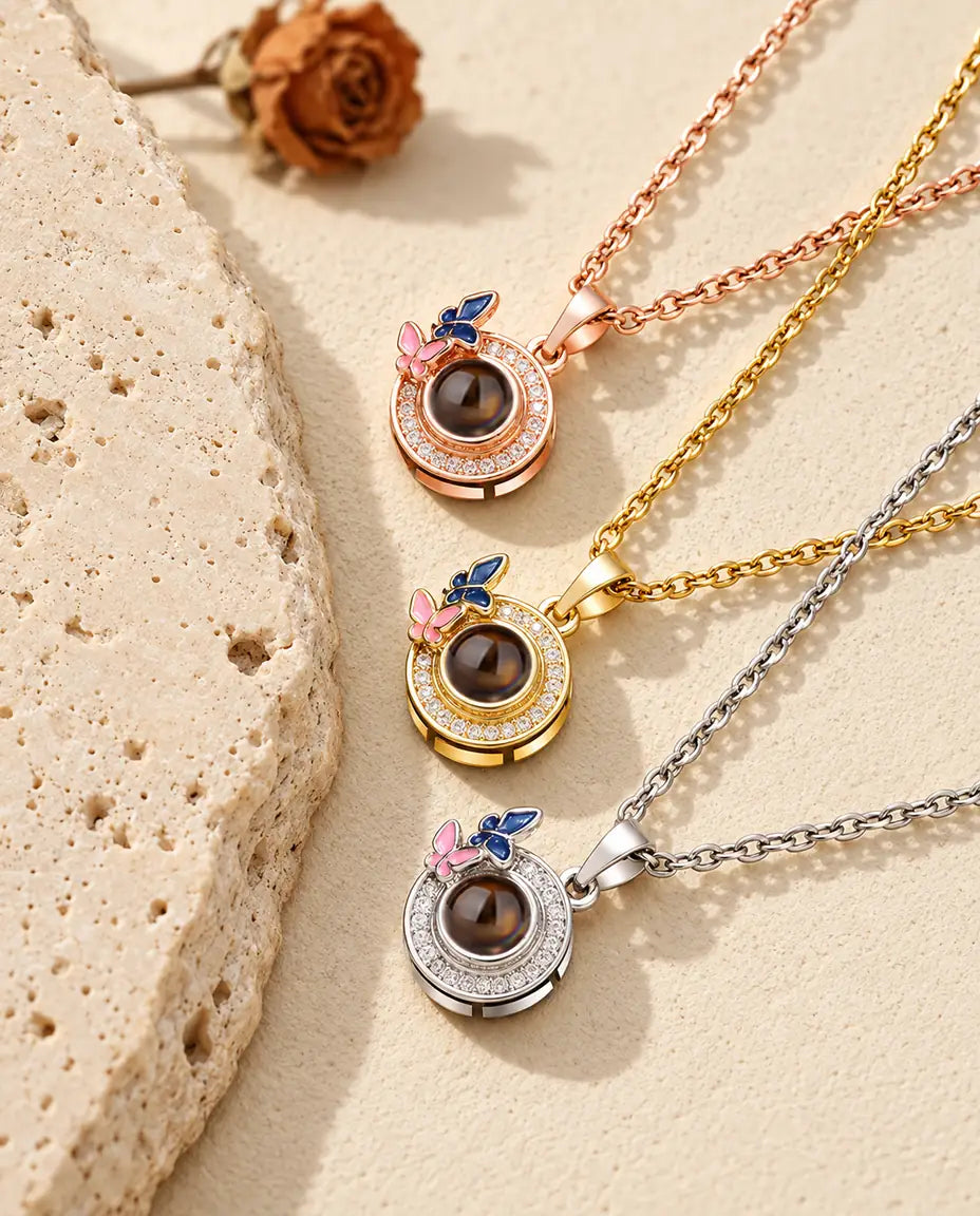 Pendentifs papillons couleur or rose, doré et argenté superposés près du travertin