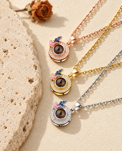 Pendentifs papillons couleur or rose, doré et argenté superposés près du travertin