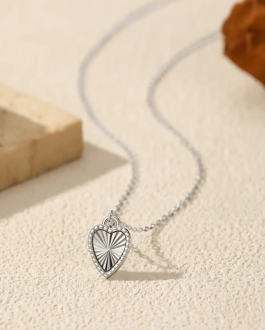 Collier Pendentif Cœur en Argent 925 - pendentif posé sur une surface claire près d’une dalle de travertin
