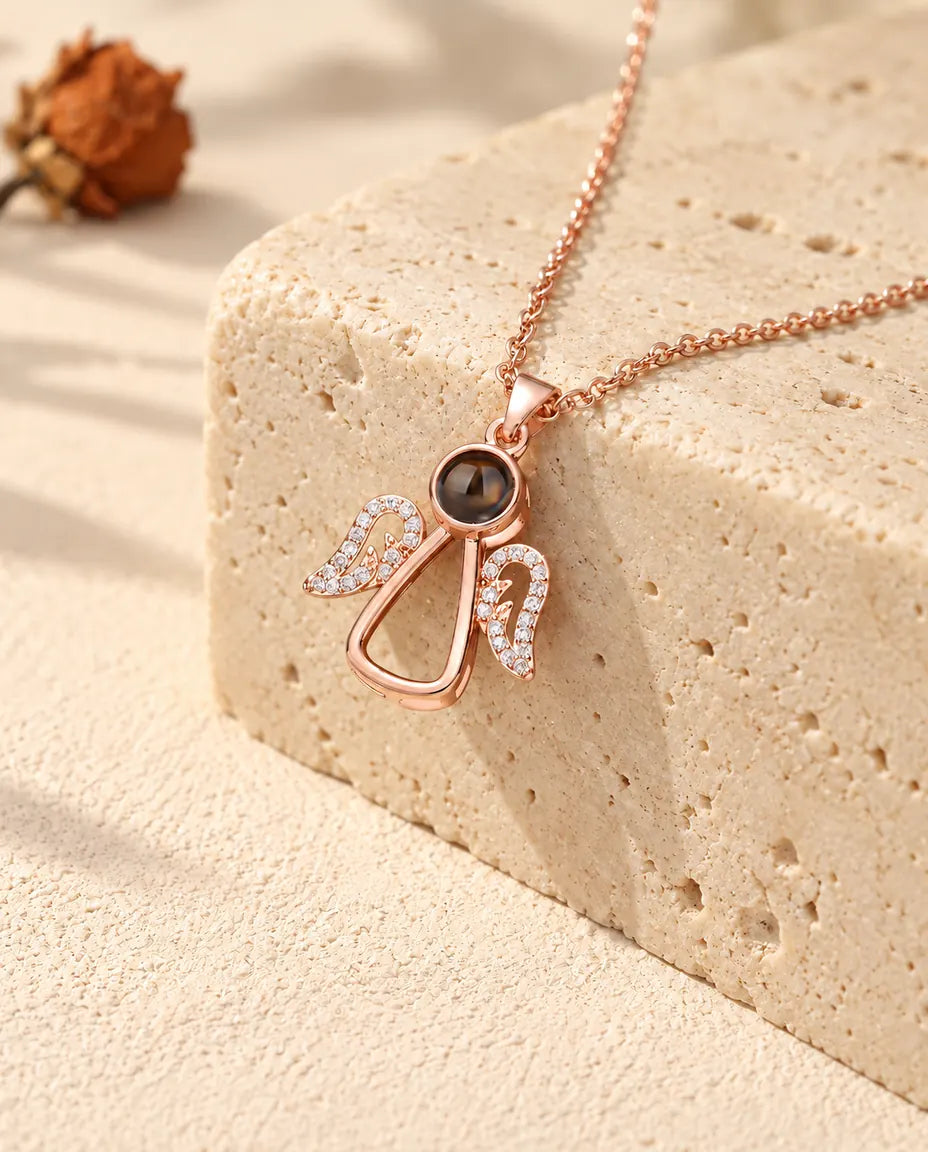 Collier ange couleur or rose posé sur du travertin