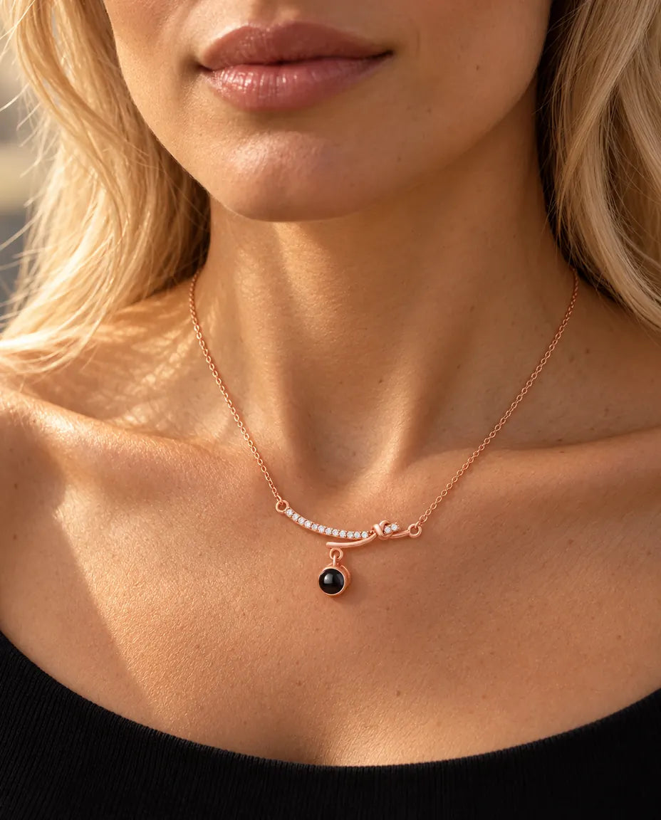 Femme en haut noir portant le collier barre courbée couleur or rose à la clavicule