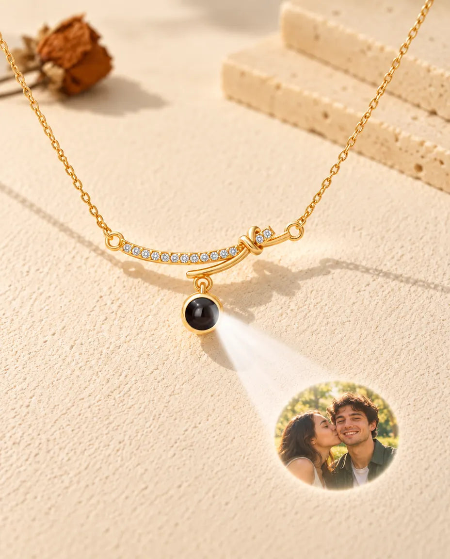 Collier barre courbée doré projetant une photo de couple sur le plâtre crème