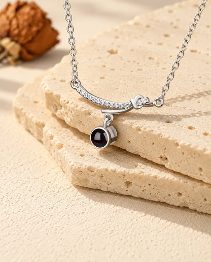 Collier barre courbée argenté posé sur le bord d'une plaque de travertin