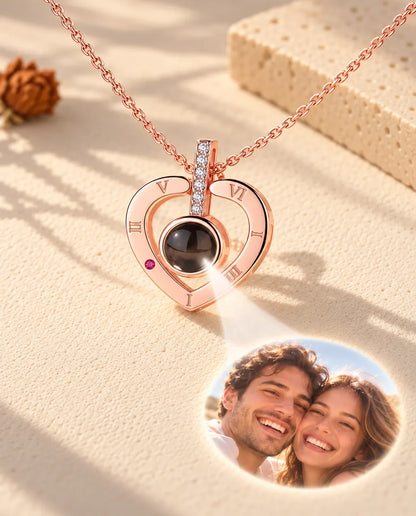 Collier cœur couleur or rose à chiffres romains projetant une photo de couple sur le plâtre