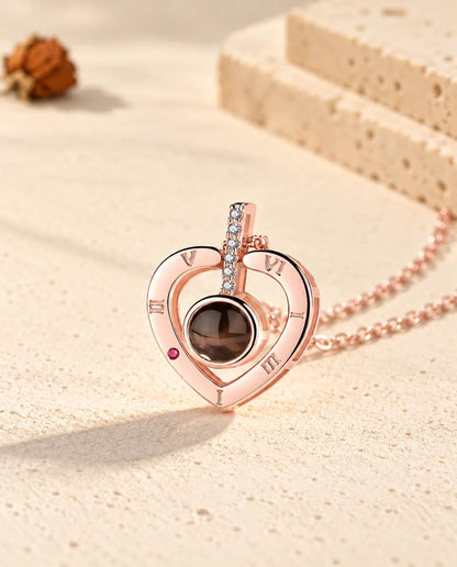 Gros plan du pendentif cœur couleur or rose avec sa barrette de zircons et ses chiffres romains