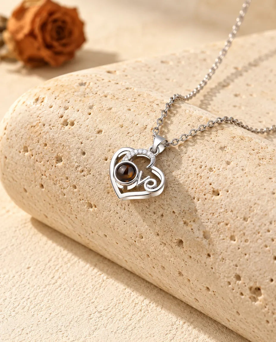 Collier photo projection cœur Love argenté avec arc de zircons, posé sur un bloc de travertin