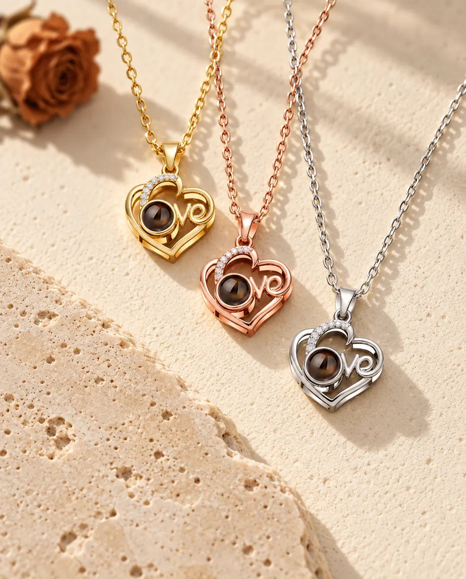 Pendentifs cœur Love doré, or rose et argenté empilés près d'une dalle de travertin