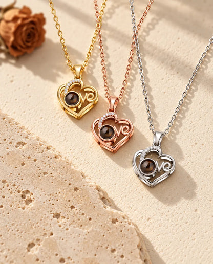 Pendentifs cœur Love doré, or rose et argenté empilés près d'une dalle de travertin