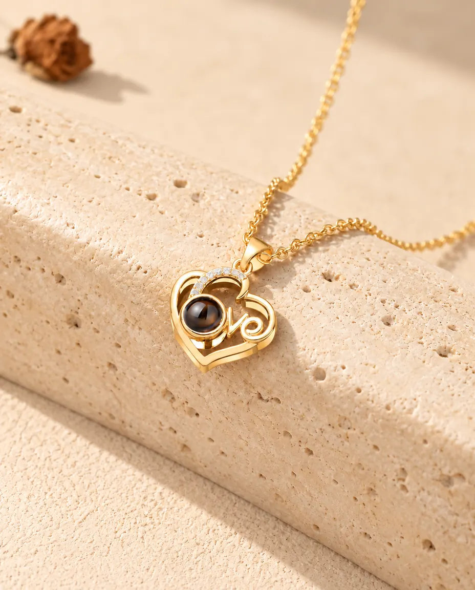 Collier photo projection cœur Love doré appuyé contre un bloc de travertin