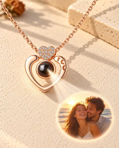 Collier cœur ouvert couleur or rose projetant une photo de couple à la plage sur le plâtre