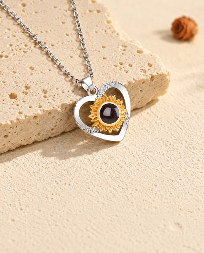 Collier cœur tournesol incliné à côté d'une plaque de travertin