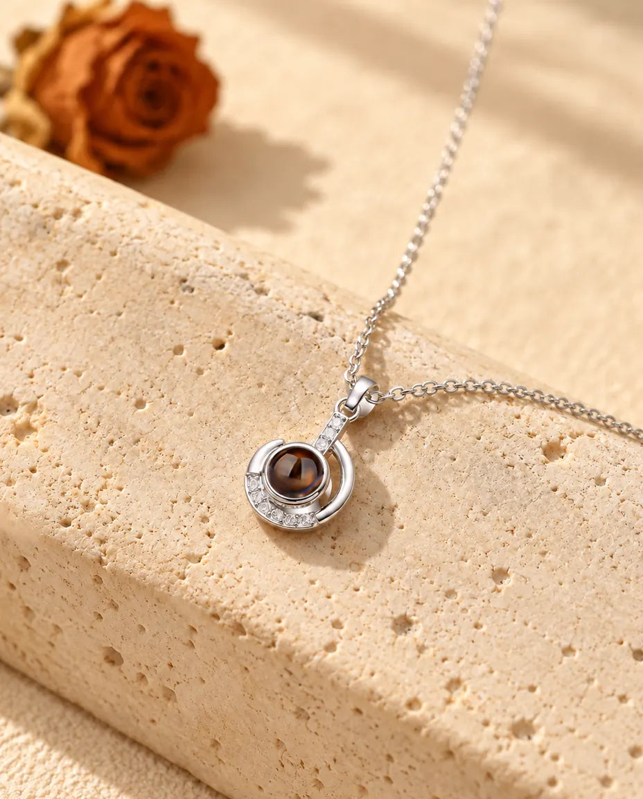 Collier croissant de lune argenté posé sur un bloc de travertin