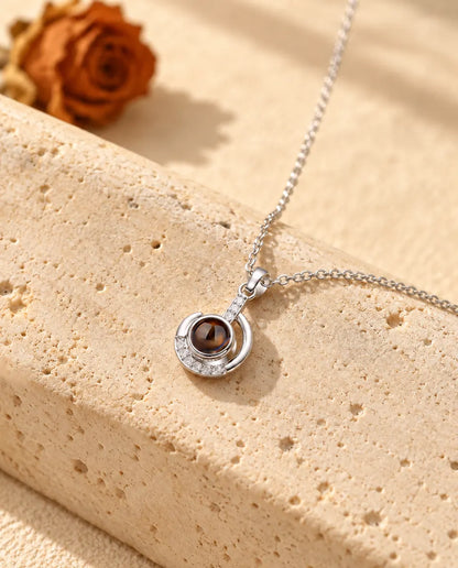 Collier croissant de lune argenté posé sur un bloc de travertin