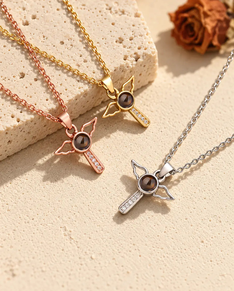 Pendentifs croix ailée couleur or rose, doré et argenté sur du travertin