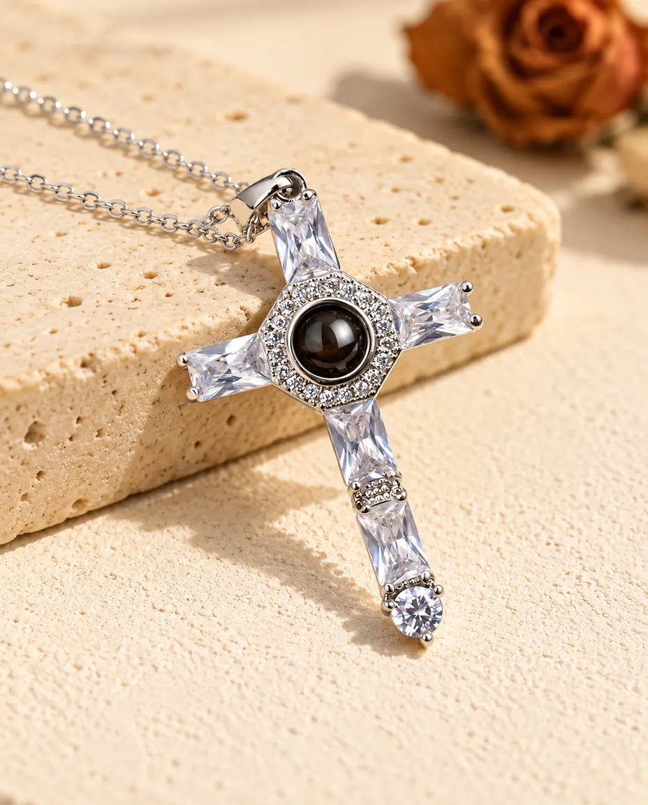 Collier croix en zircons argenté avec photo dans la pierre posé contre du travertin
