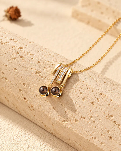 Pendentif doré serti de zircons avec deux pierres rondes sur du travertin